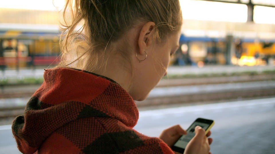 Das bild zeigt ein Frau, die am Handy ist, symbolisch dafür, dass die Menschen heutzutage oft am Smartphone sind.